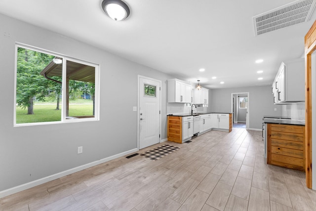 kitchen with light hardwood / wood-style floors, white cabinets, sink, and white dishwasher