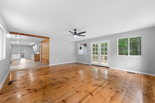 unfurnished living room featuring light wood-type flooring, ceiling fan, and french doors