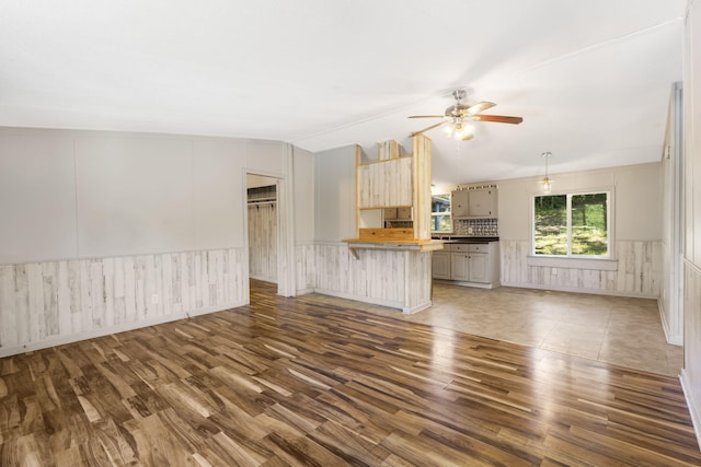 unfurnished living room featuring lofted ceiling, ceiling fan, and dark wood-type flooring