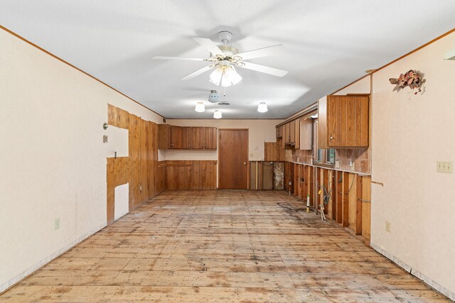 kitchen with ceiling fan, light hardwood / wood-style flooring, and wood walls