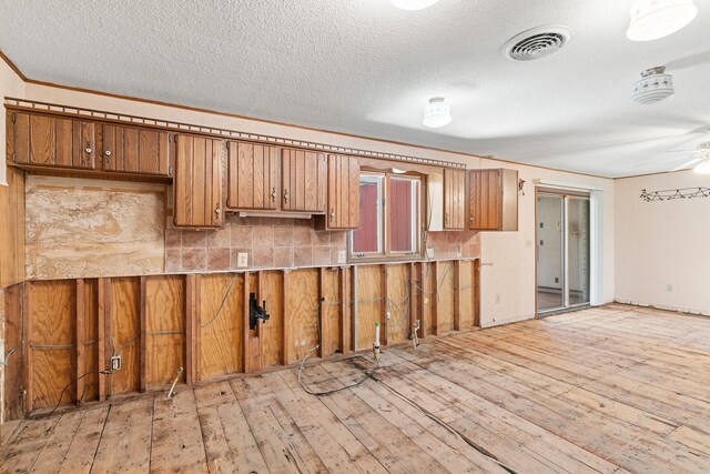 kitchen featuring ceiling fan, a textured ceiling, light hardwood / wood-style flooring, and backsplash