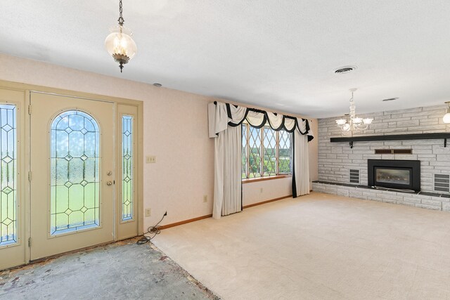 carpeted entrance foyer featuring a fireplace, an inviting chandelier, and a textured ceiling