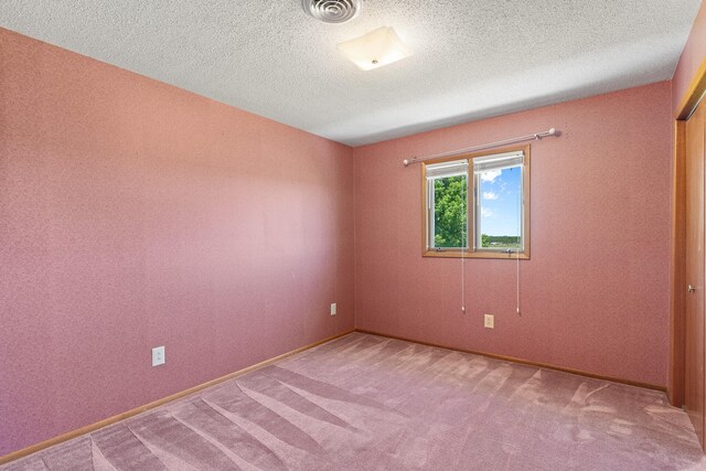 carpeted spare room with a textured ceiling