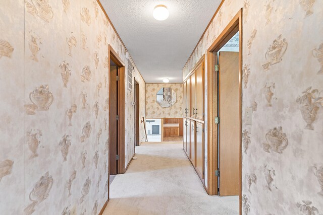 hallway with light carpet and a textured ceiling