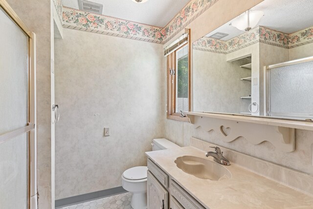 bathroom with vanity, a shower with door, tile patterned floors, toilet, and a textured ceiling