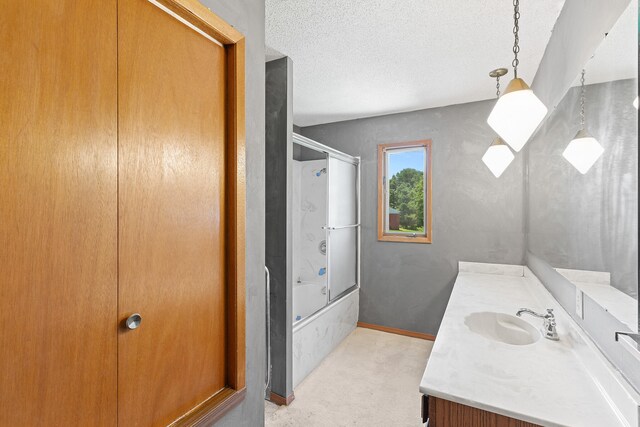 bathroom featuring bath / shower combo with glass door, vanity, and a textured ceiling