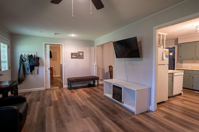 living room featuring ceiling fan, a textured ceiling, and dark hardwood / wood-style floors