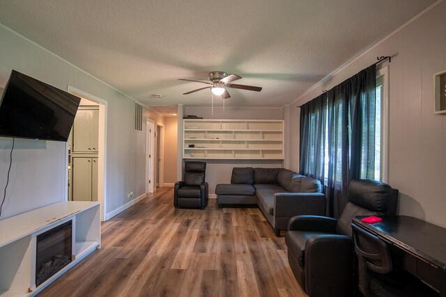 living room with crown molding, wood-type flooring, and a textured ceiling