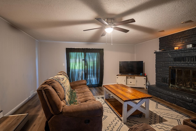 living room featuring a fireplace, ceiling fan, hardwood / wood-style floors, and a textured ceiling