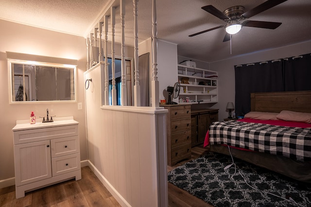 bedroom with hardwood / wood-style flooring, ceiling fan, sink, and a textured ceiling