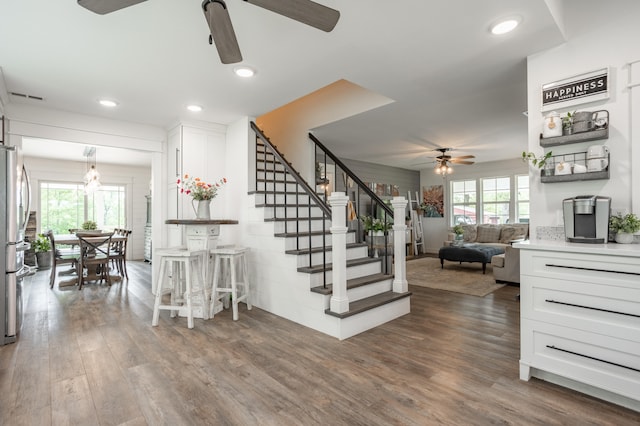 stairway with a healthy amount of sunlight, ceiling fan, and hardwood / wood-style floors