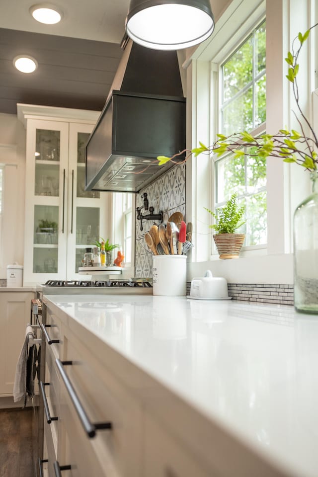 kitchen with wall chimney range hood, white cabinetry, and dark hardwood / wood-style flooring