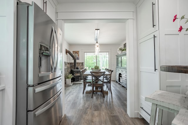 kitchen featuring stainless steel fridge, a wood stove, dark hardwood / wood-style floors, and white cabinets