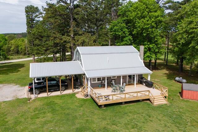 back of property featuring a wooden deck, a yard, and a carport