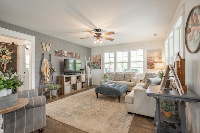 living room with dark hardwood / wood-style flooring, wooden walls, and ceiling fan