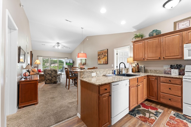 kitchen with kitchen peninsula, sink, white appliances, and vaulted ceiling