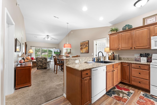 kitchen featuring a peninsula, a sink, open floor plan, lofted ceiling, and white appliances