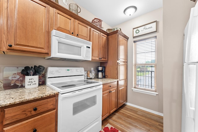 kitchen featuring light wood-style flooring, baseboards, brown cabinetry, and white appliances