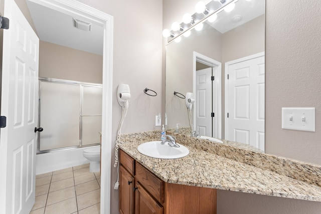 bathroom with tile patterned floors, bath / shower combo with glass door, toilet, visible vents, and vanity