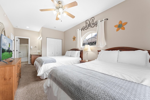 bedroom with light colored carpet, ceiling fan, ensuite bath, and a closet