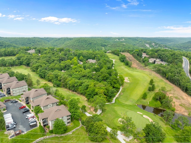 drone / aerial view with a view of trees, a water view, and view of golf course