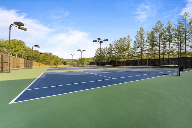 view of tennis court featuring community basketball court and fence