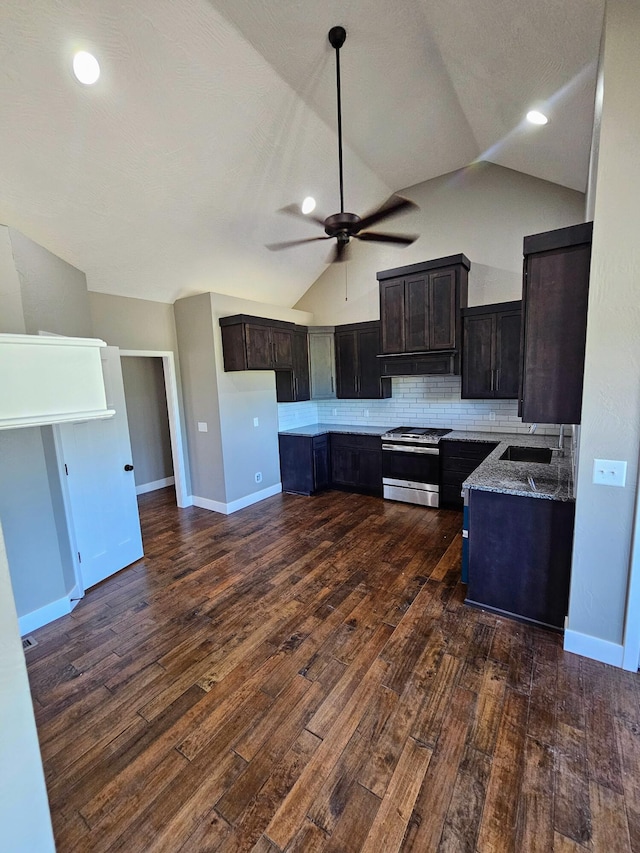 kitchen with light stone counters, dark wood-type flooring, vaulted ceiling, and gas range