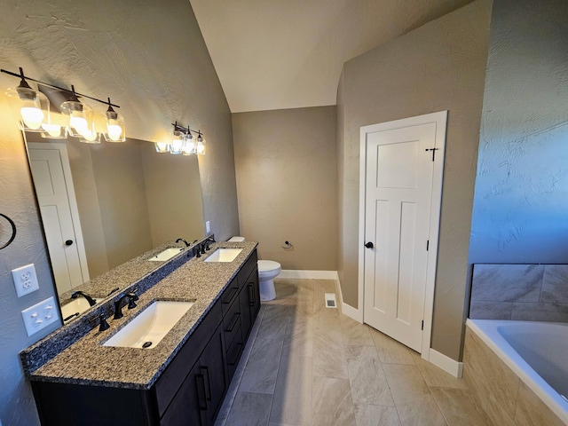 bathroom with a relaxing tiled tub, vanity, lofted ceiling, and toilet