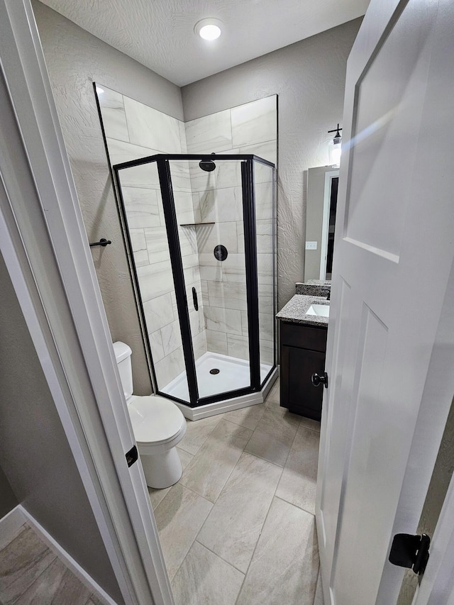 bathroom featuring vanity, toilet, an enclosed shower, a textured ceiling, and tile patterned flooring