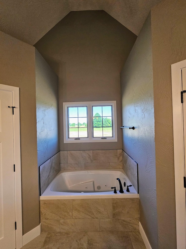 bathroom with tiled bath, lofted ceiling, and a textured ceiling