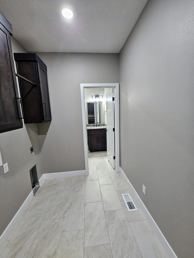 laundry room featuring a textured ceiling, hookup for an electric dryer, and cabinets