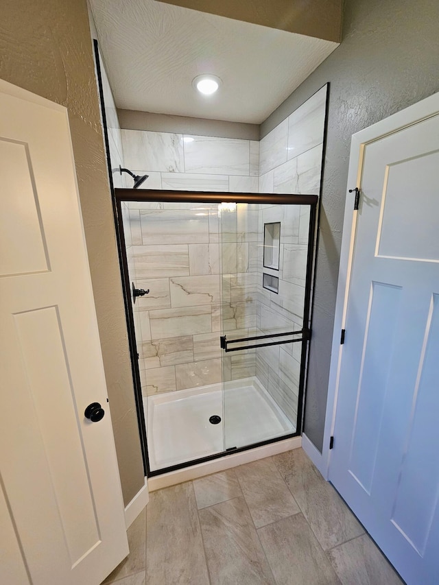 bathroom with a shower with shower door and tile patterned floors