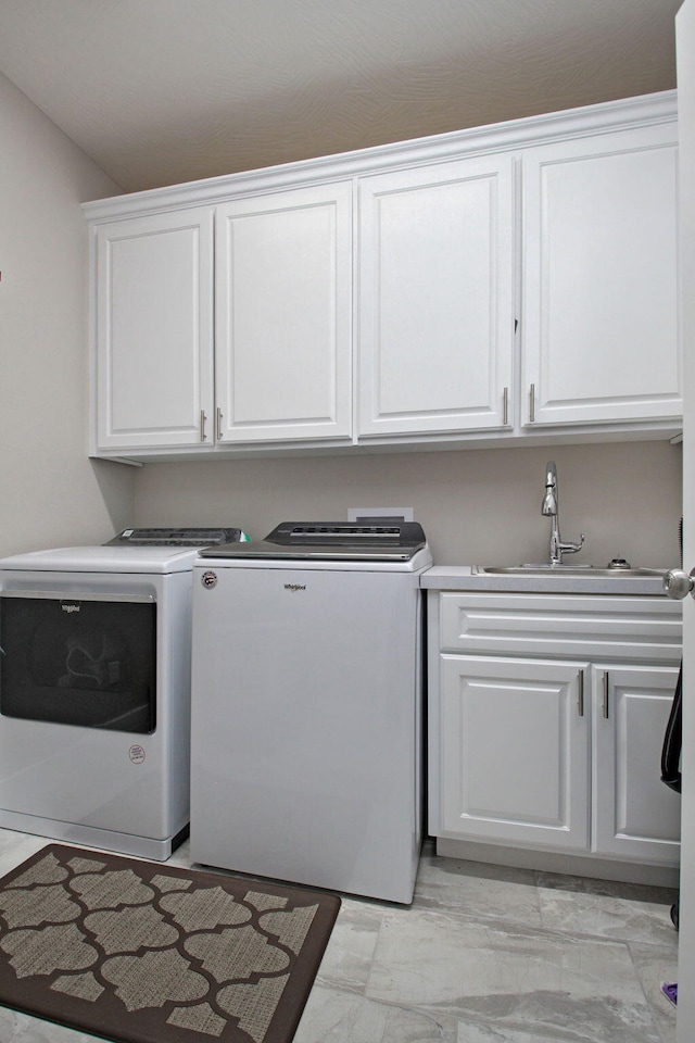 washroom with marble finish floor, washing machine and clothes dryer, cabinet space, and a sink