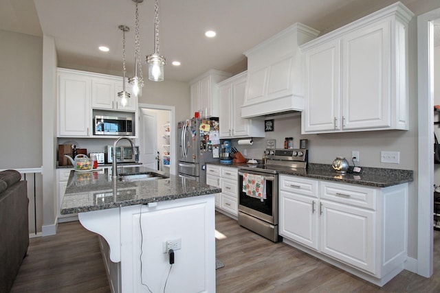 kitchen with hanging light fixtures, appliances with stainless steel finishes, sink, and white cabinetry