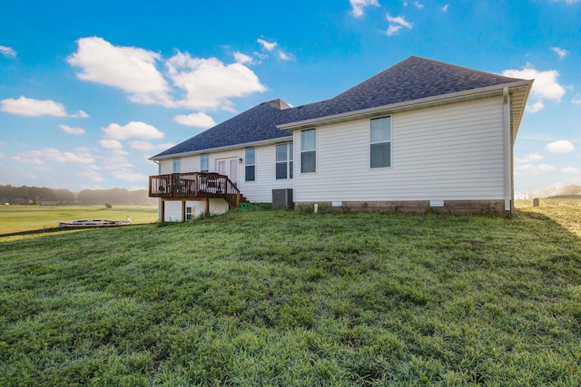 back of property featuring a wooden deck, roof with shingles, a yard, and central AC unit