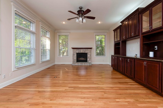 unfurnished living room with a fireplace, ornamental molding, light wood-type flooring, and ceiling fan