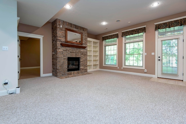 unfurnished living room with light carpet, a fireplace, and built in shelves