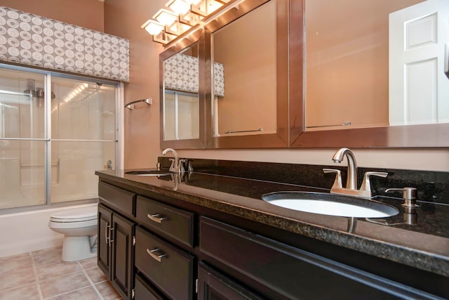 full bathroom with tile patterned flooring, vanity, bath / shower combo with glass door, and toilet