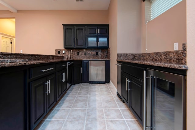 kitchen with wine cooler, stainless steel fridge, light tile patterned floors, tasteful backsplash, and dark stone countertops