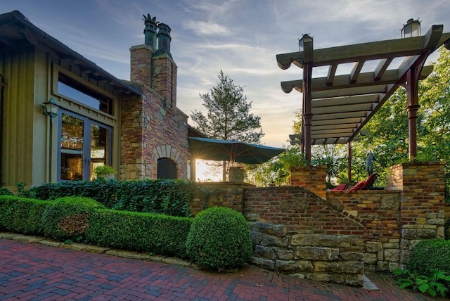 property exterior at dusk with a patio and a pergola