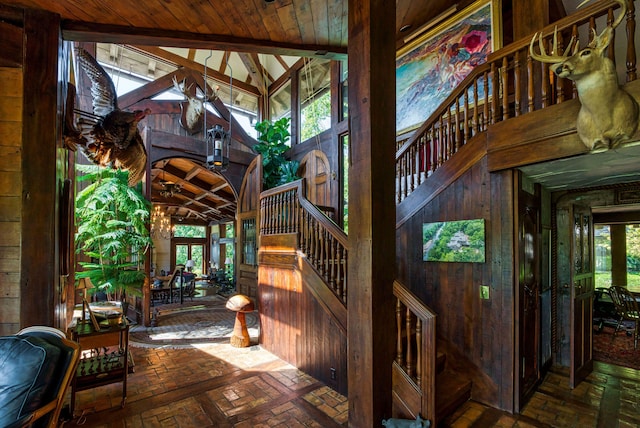 stairs with wood walls, vaulted ceiling, and wood ceiling