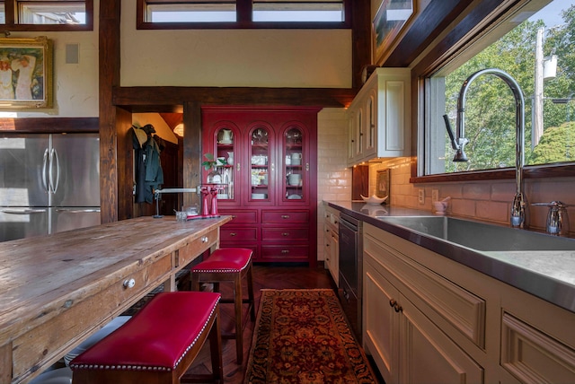 kitchen featuring tasteful backsplash, stainless steel refrigerator, sink, and black dishwasher