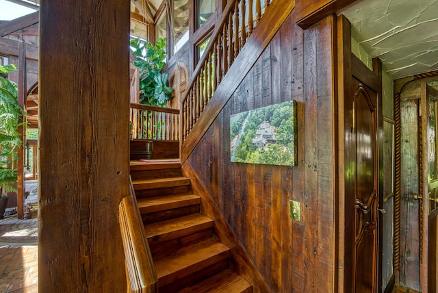 stairway with wooden walls and a healthy amount of sunlight