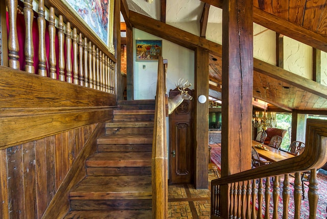 stairs featuring wood walls and vaulted ceiling