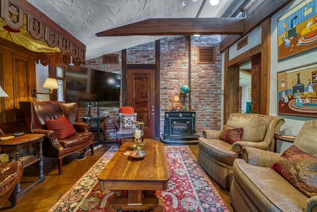 living room featuring brick wall, hardwood / wood-style floors, vaulted ceiling with beams, and a wood stove