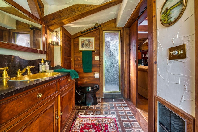 bathroom featuring wood walls, vaulted ceiling, vanity, and toilet