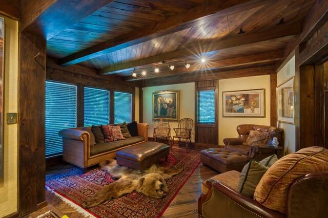 living room with a healthy amount of sunlight, beam ceiling, hardwood / wood-style floors, and wooden ceiling