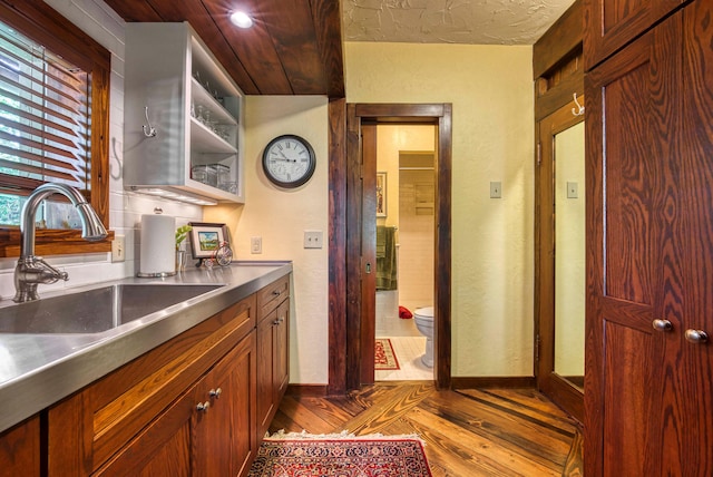 kitchen with stainless steel counters, light wood-type flooring, and sink