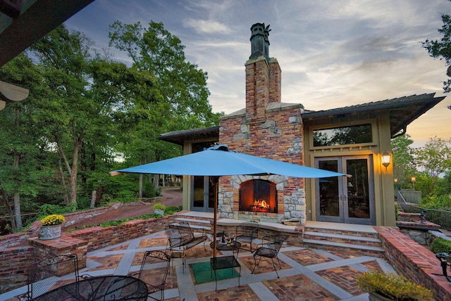 patio terrace at dusk with an outdoor stone fireplace