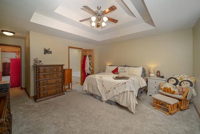 bedroom featuring a raised ceiling, light colored carpet, and ceiling fan